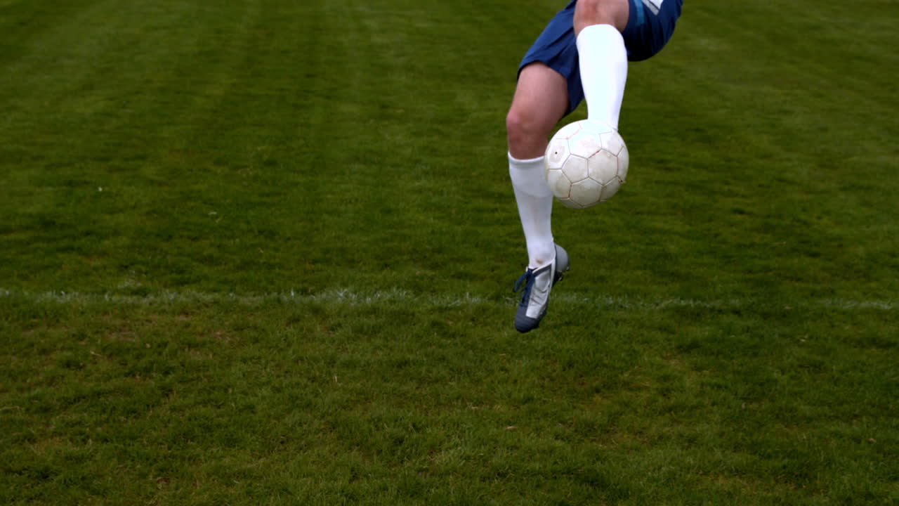 Football player in blue kicking the ball on pitch