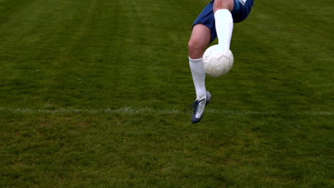 football player in blue kicking the ball on pitch
