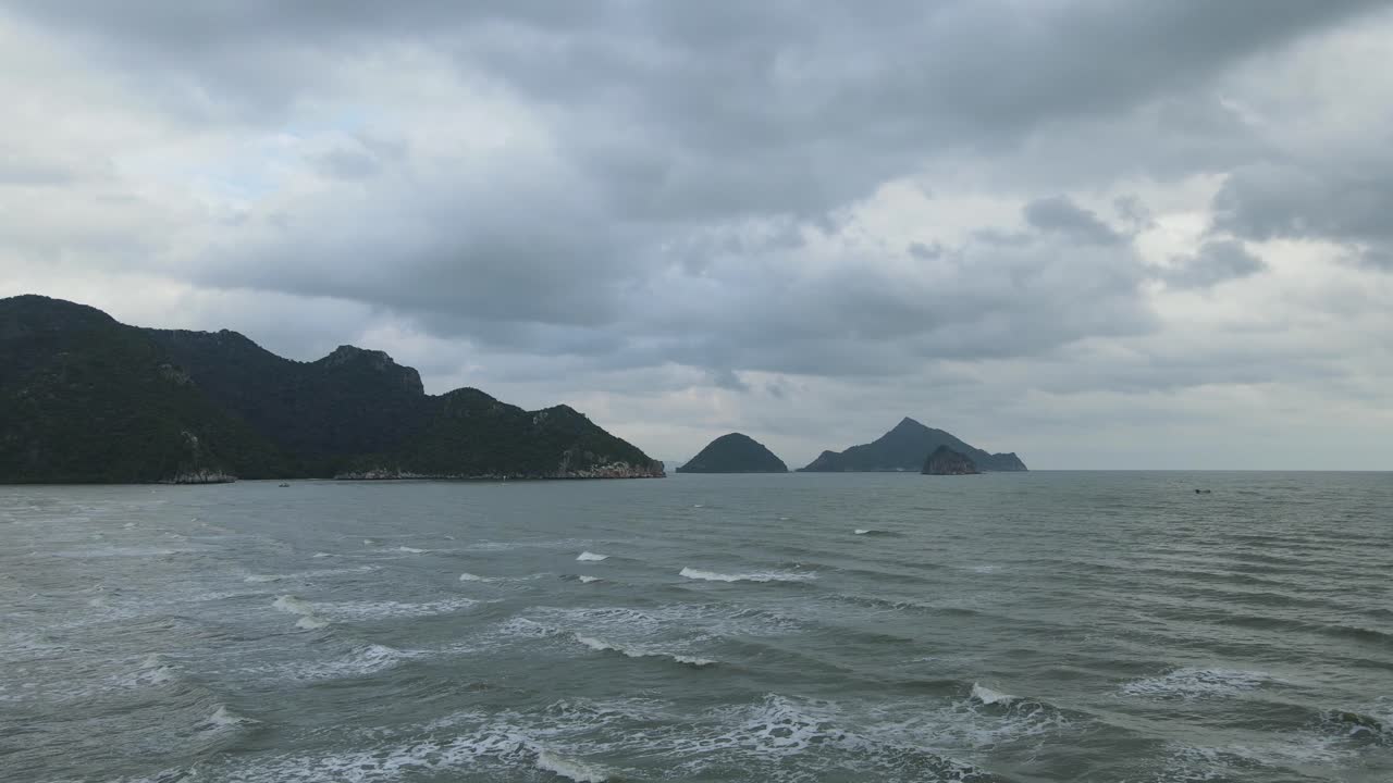 석회암 산, 섬, 회색 구름이 있는 이 멋진 바다 풍경을 보여주는 공중 상승 영상