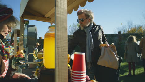 mature man shopping at local farmers market mature man shopping at local farmers market he takes paper eco bag with fruits and vegetables autumn fair on weekend outdoors vegetarian and organic food agriculture points of sale system