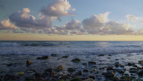 Olas-Del-Océano-En-Cámara-Lenta-En-Una-Playa-Rocosa-Con-Un-Cielo-Dramático-En-El-Fondo