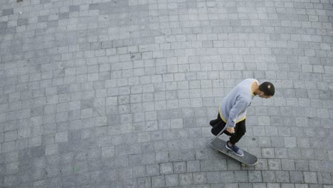 top view of skill man with one leg on crutches riding his skateboard on circles.