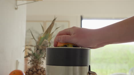 Persona-Exprimiendo-Naranja-En-Un-Exprimidor-Eléctrico-En-Una-Soleada-Cocina