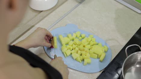 Woman-cutting-potato-on-the-blue-cutting-board