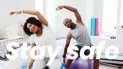Animation-os-stay-safe-text-over-man-and-woman-exercising-with-swiss-balls-at-home