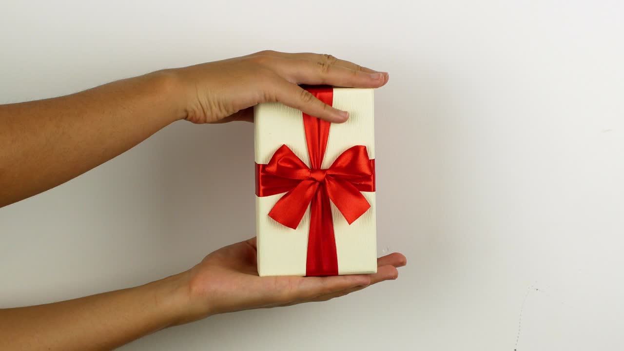 mujer con la mano sosteniendo un regalo para feliz navidad. regalo de año nuevo y navidad en cajas brillantes con un arco sorpresa. video en 4k de un primer plano de una caja de regalos.