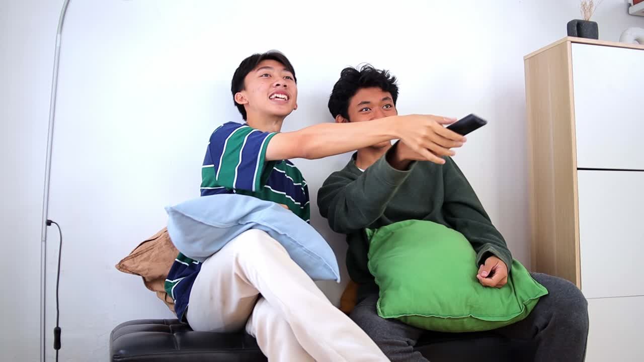 Friends sitting watching TV together and fighting over the TV remote