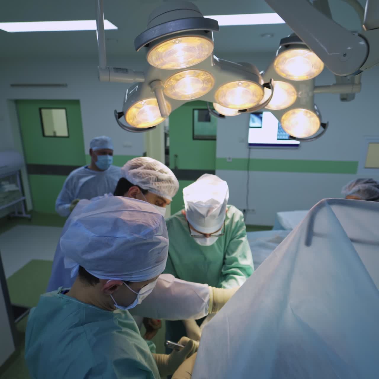 Three surgeons cooperating during the surgery. Co working of the professional doctors in the big surgical theatre