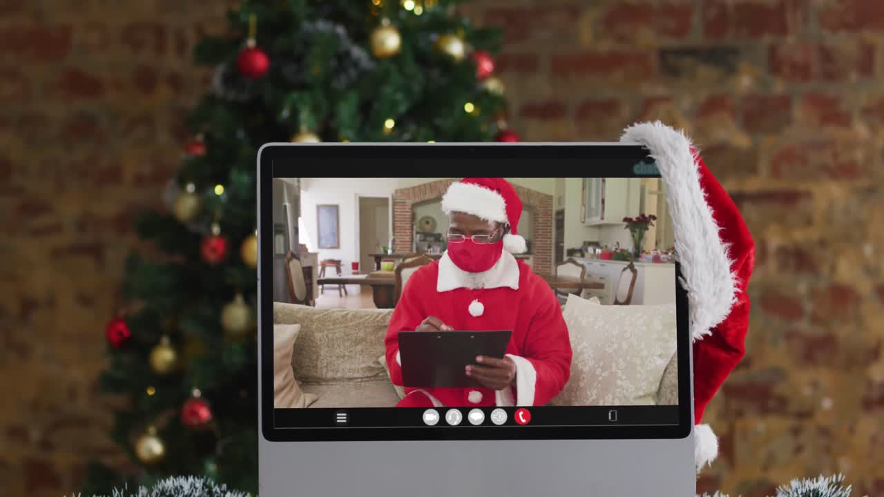 santa afroamericano con máscara de cara en una videollamada, con árbol de navidad