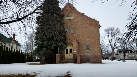 exterior del día que establece la toma de la entrada principal de la antigua iglesia abandonada en invierno con nieve