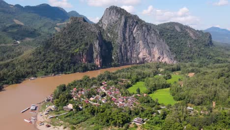 aerial view of mekong river beside local village town and towering cliffs in luang prabang