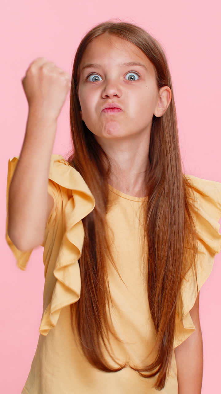 Child girl kid angrily shaking fist in funny way expressing dissatisfaction or playful mock threat