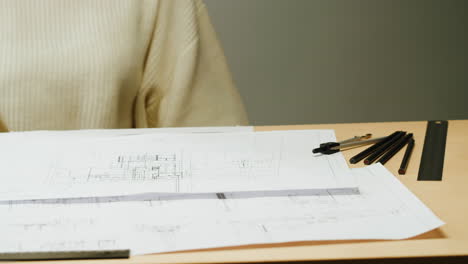 person examining architectural blueprints on a desk