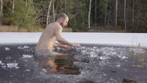 slow motion - a male ice bather gets up out of the freezing water