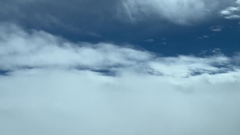 Aerial-view-from-a-cockpit-while-flying-between-layers-of-soft-white-clouds-and-blue-sky