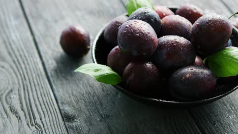 wet purple plums in bowl