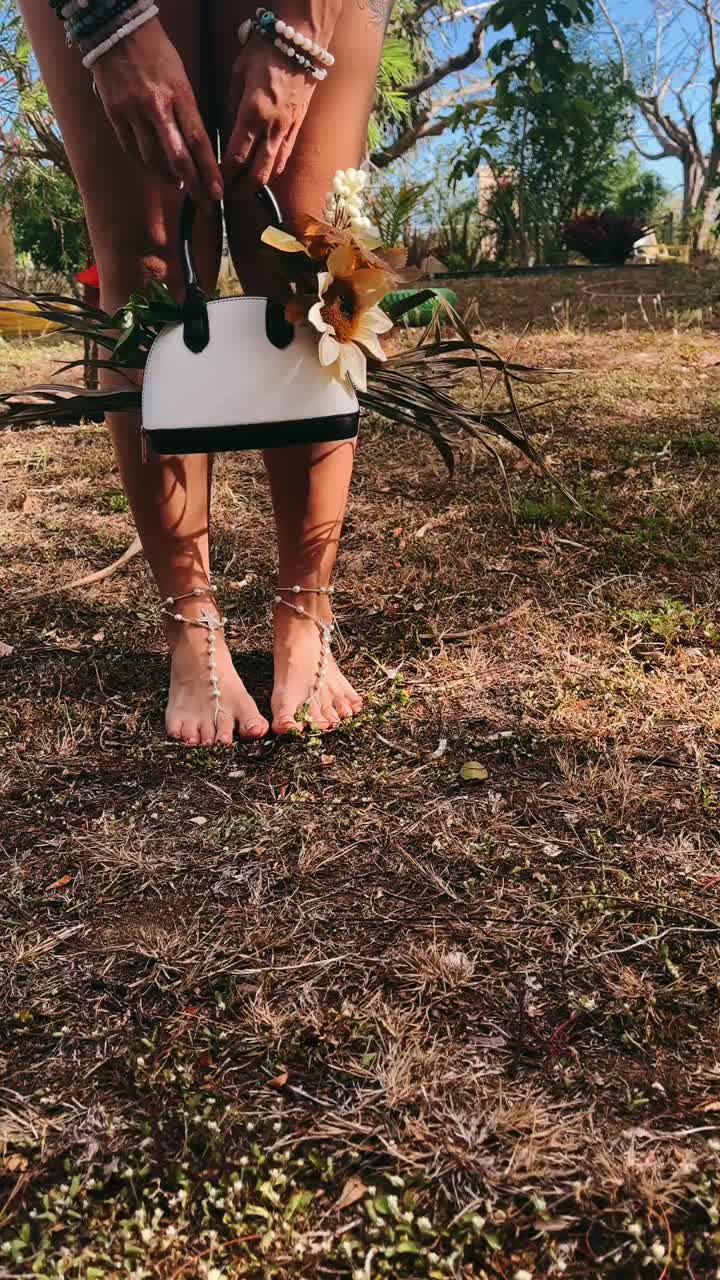 mujer en un jardín con un bolso y un arreglo de flores