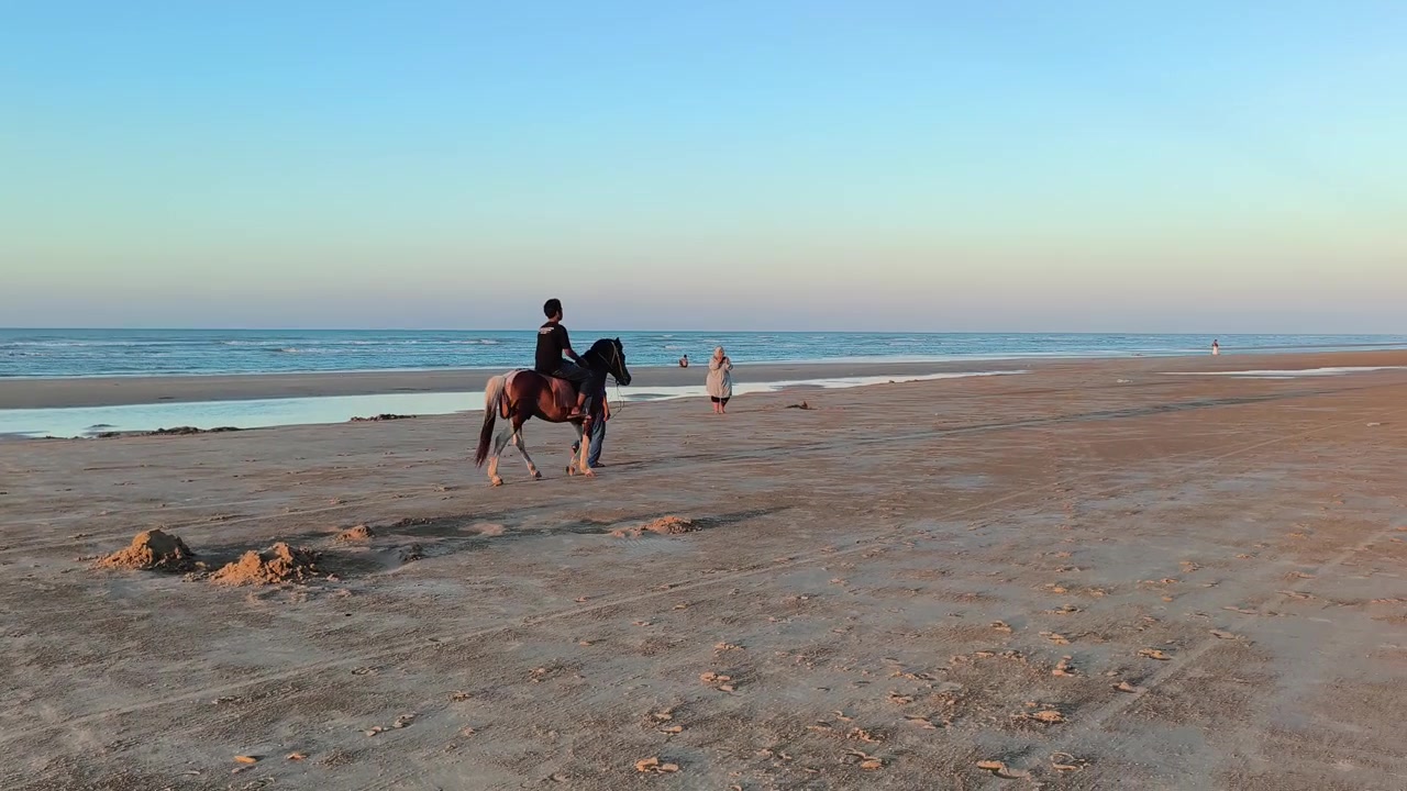 Persona a cavallo sulla spiaggia sabbiosa al tramonto