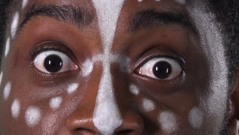 rostro de un hombre afroamericano con un patrón étnico blanco. hombre negro con miedo mirando directamente a la cámara. pantalla verde, tecla de croma. ojos cerrados, retrato macro