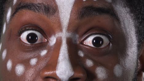 face of an african american man with an ethnic white pattern. black male with fear looking straight into the camera. green screen, chroma key. close up eyes, macro portrait