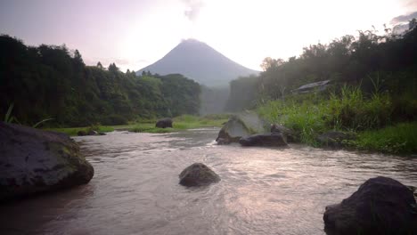 Mountain-rocky-river-with-volcano-that-emits-smoke-on-the-background---beautiful-nature-footage-in-jungle