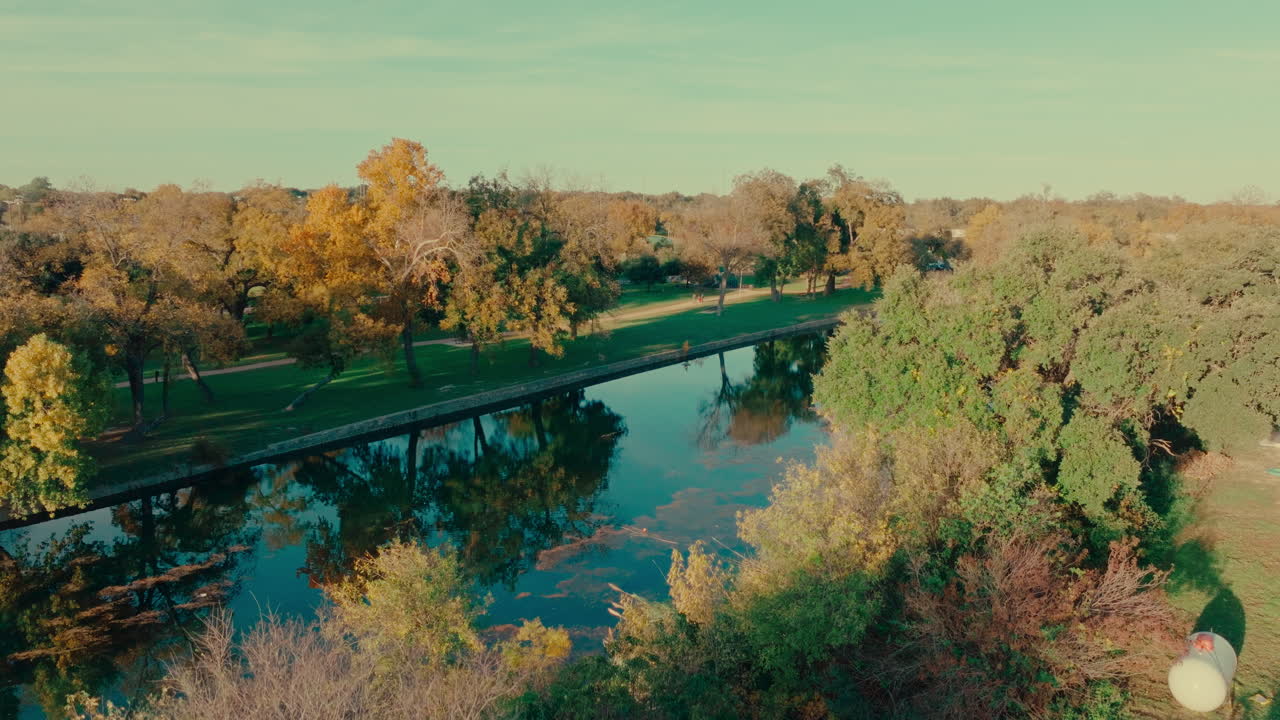 텍사스 주 조지타운에 있는 샌 가브리엘 강 (san gabriel river) 에 있는 공중 무인기 (aerial drone) 는 4k 영상으로 가을의 나무 위에서 어두워지면서 아오른다.