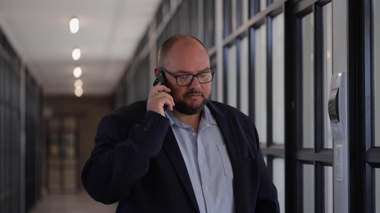 Mand i forretningstøj, der taler i telefon på gangen