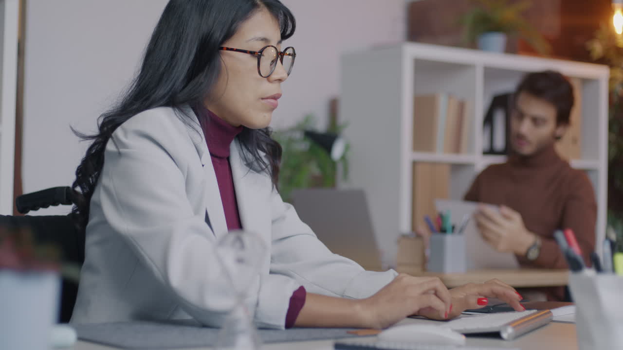 Woman in Wheelchair Working at a Computer in an Office