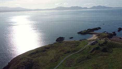 aerial view circles ynys llanddwyn island with hazy snowdonia mountain range across shimmering irish sea