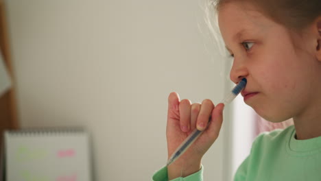 Pensive schoolgirl presses pen to nose and purses lips