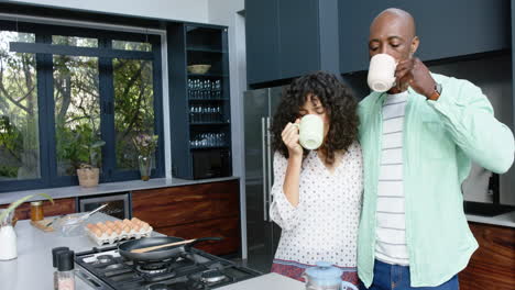 Glückliches-Biracial-Paar-Umarmt-Und-Gießt-Kaffee-In-Der-Küche-Ein,-Zeitlupe