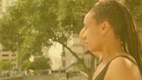 animation of caucasian young woman in activewear adjusting dreadlocks while looking away in city