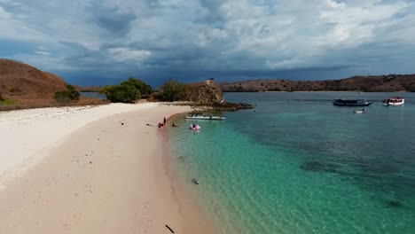 Vista-Aérea-De-Botes-Y-Personas-En-Una-Playa,-En-El-Parque-Nacional-De-Komodo,-Labuan-Bajo,-Indonesia---Dolly,-Drone-Shot