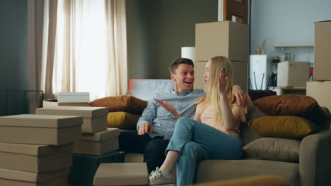 couple talking new home interior discussing design sitting at comfortable couch.