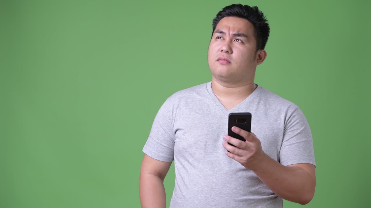 초록색 배경에 젊은 잘생긴 과체중 아시아인