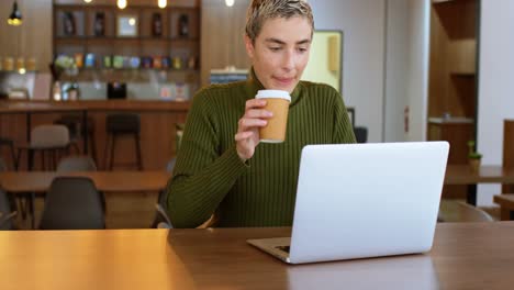 Executive-having-coffee-while-using-laptop-in-office-cafeteria-4k