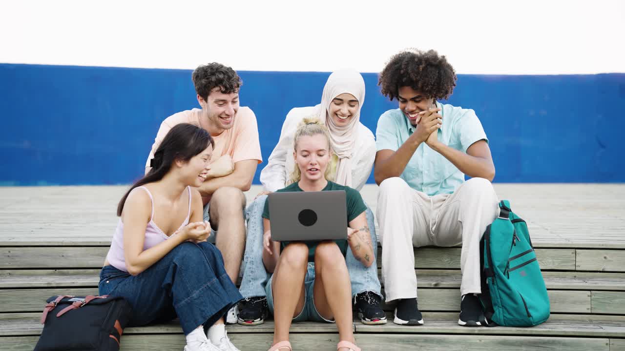 Mangfoldig gruppe studerende fejrer med en bærbar computer
