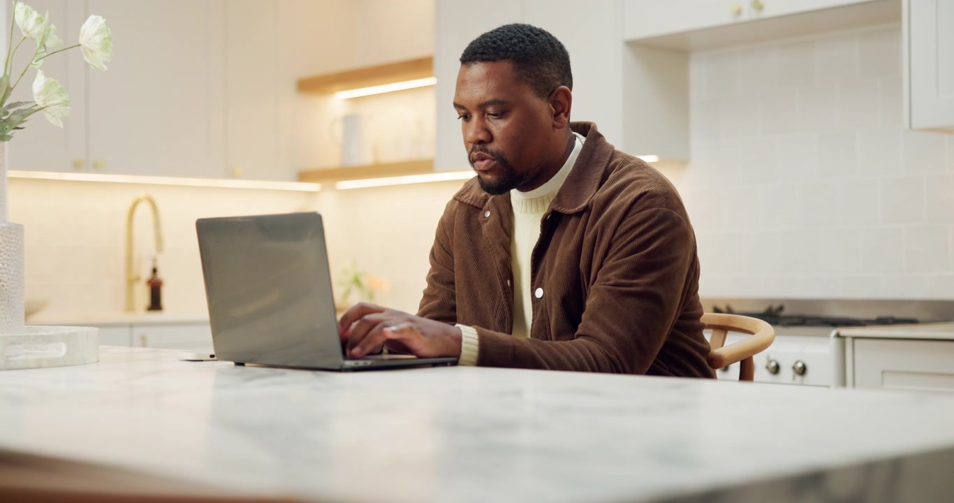 Focused Man Working on Laptop at Kitchen Counter