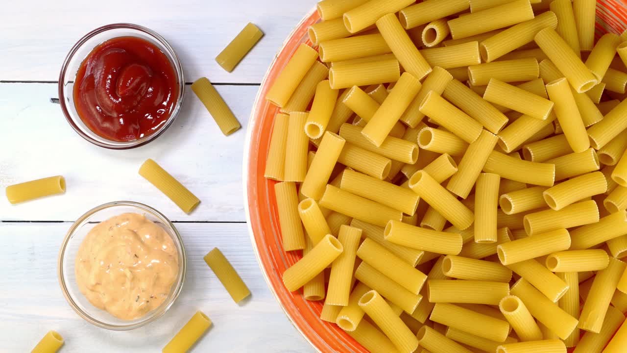 pasta italiana rigatoni cruda sin cocinar girando lentamente en la mesa giratoria en el plato.