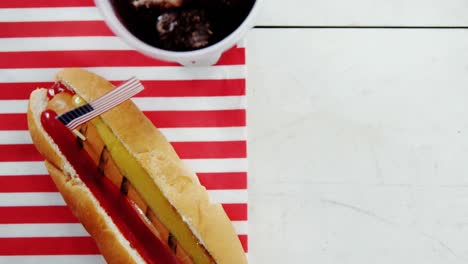 perro caliente y bebida fría servida en una mesa de madera con tema del 4 de julio