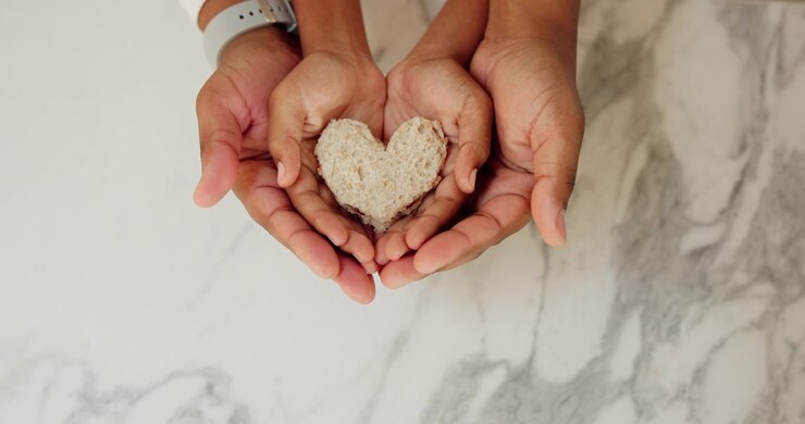 Genitore e figlio che tengono insieme un pane a forma di cuore