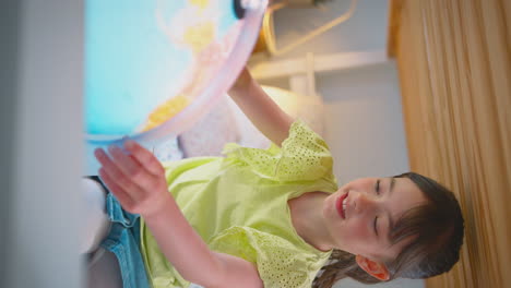 Vertikales-Video-Eines-Mädchens-Im-Schlafzimmer,-Das-Auf-Dem-Bett-Liegt-Und-Einen-Laptop-Mit-Beleuchtetem-Globus-Benutzt