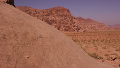 The-camera-moves-past-a-sandstone-formation-to-reveal-the-vast-Saudi-desert-of-Wadi-Rum