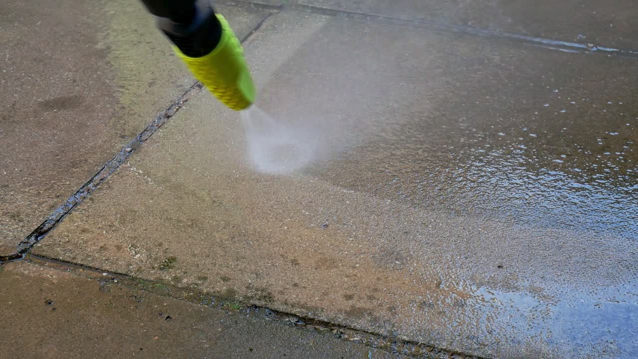 Cleaning patio slabs with a black and green pressure washer