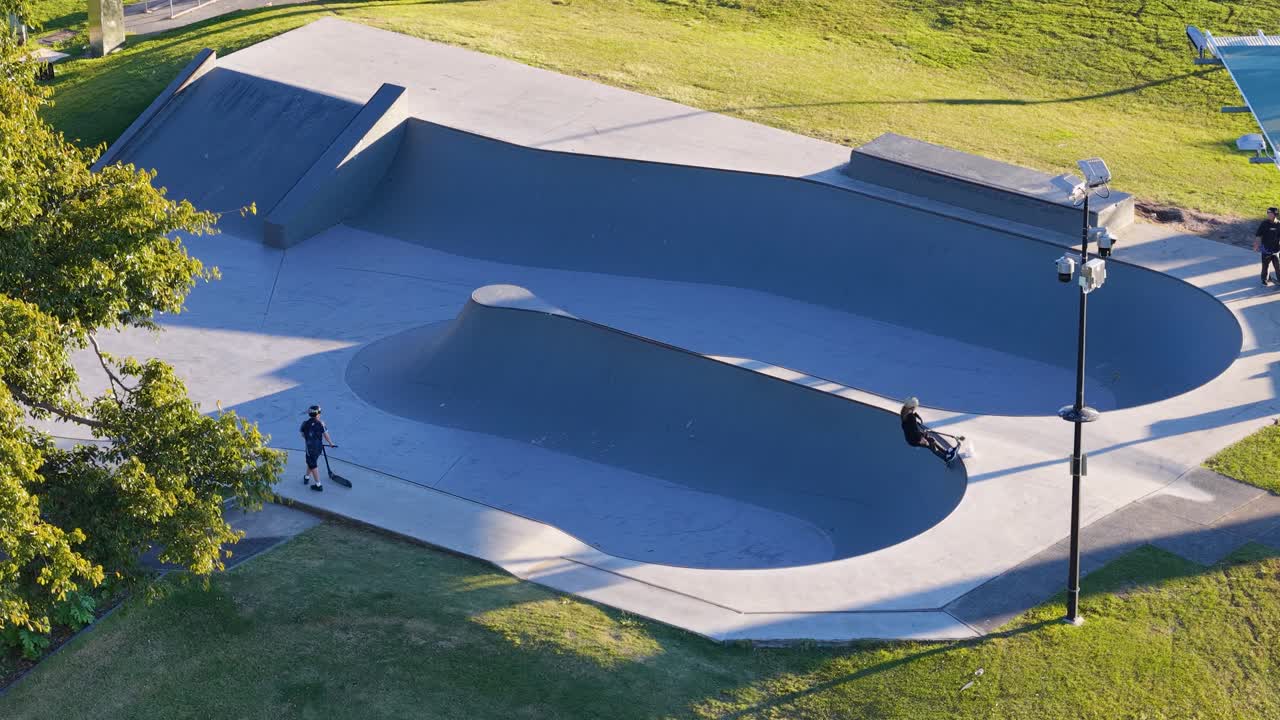 Children skateboarding in a sunlit skate park bowl, showcasing dynamic movement and youthful energy in an outdoor setting
