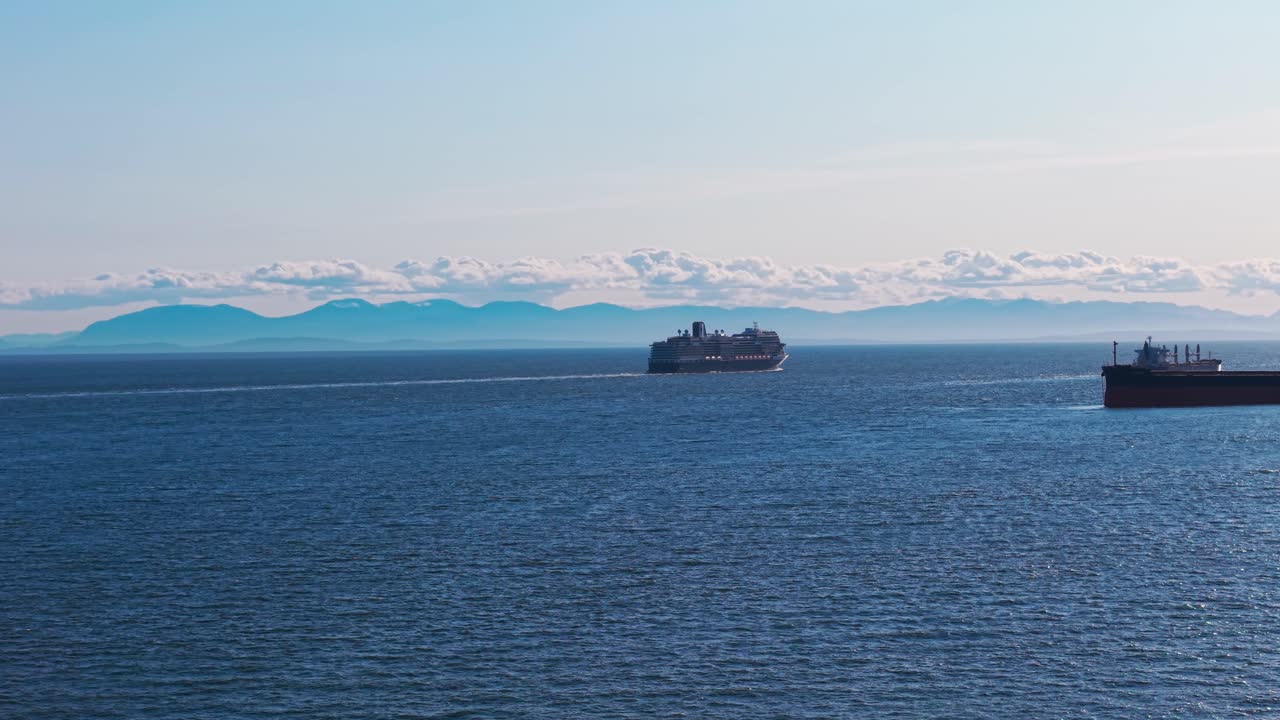 An aerial drone shot of a cruise ship under a clear blue sky on the beautiful seas of West Vancouver with the mountains of Vancouver Island over the horizon