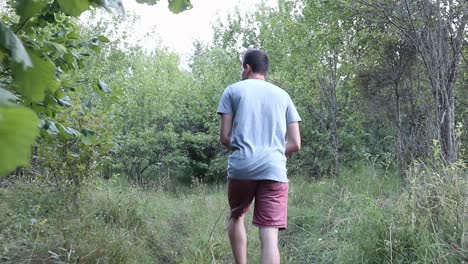 Un-Hombre-Camina-Por-Un-Sendero-En-El-Bosque,-Durante-El-Día,-Temporada-De-Verano