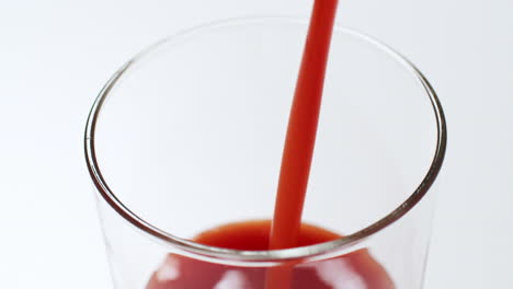 filling a glass with a refreshingly cold tomato juice as it bubbles up to its brim, and dripping some of it on the sides of the glass