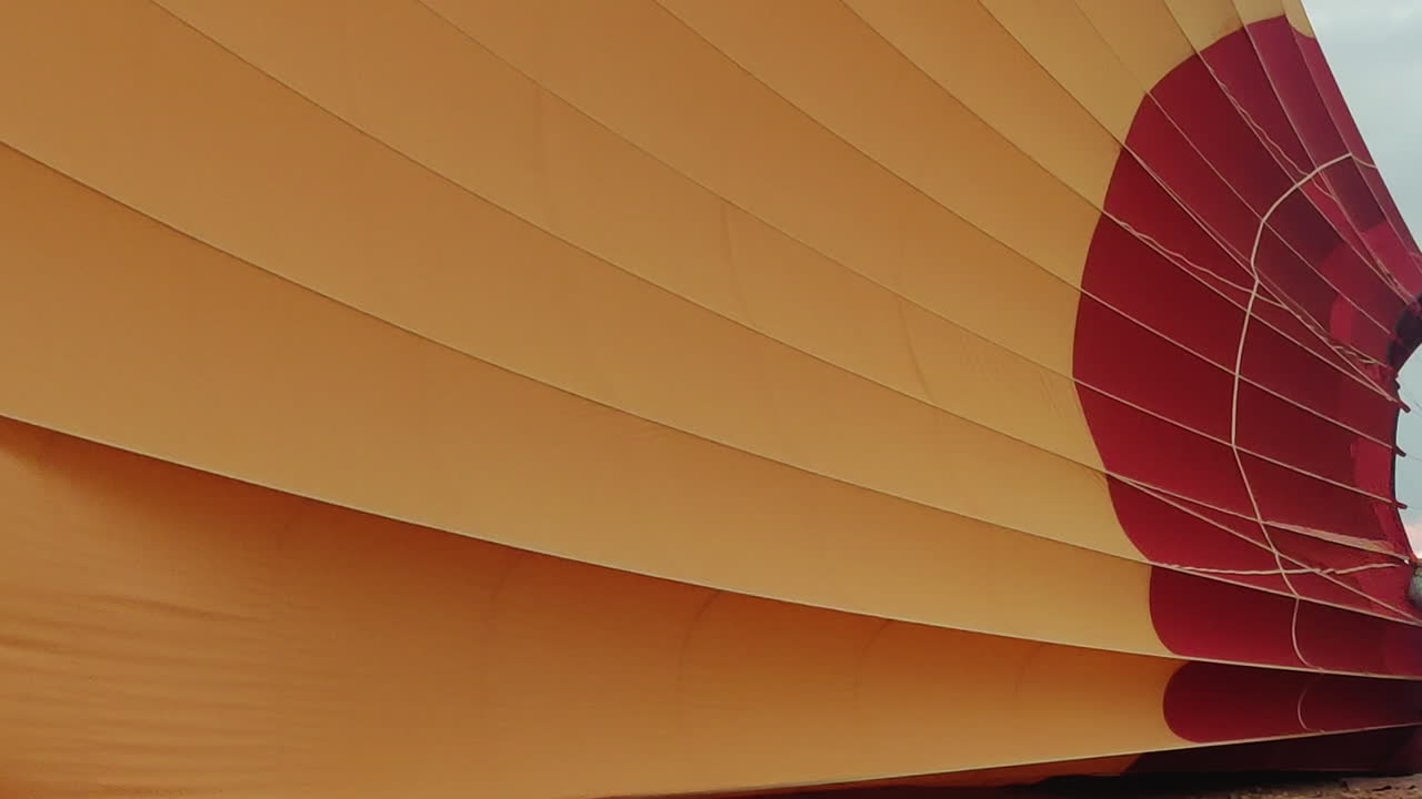 A hot air balloon being inflated with bright orange and red panels filling with air