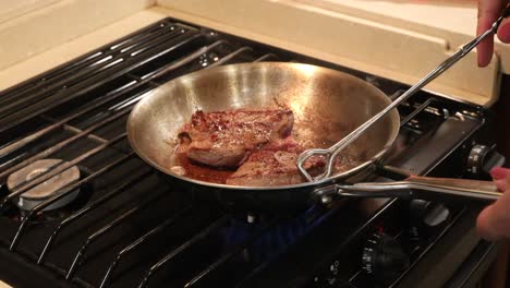 butterflied lion steak frying in a skillet on a stove top